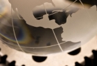 Glass globe on metal gears tinted gold,