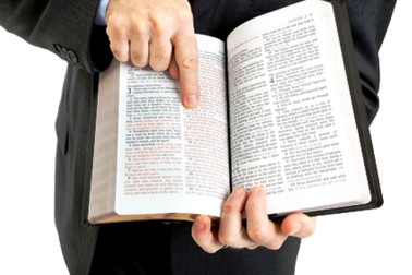 Businessman or minister holding a bible open to John 3:16.  White background.