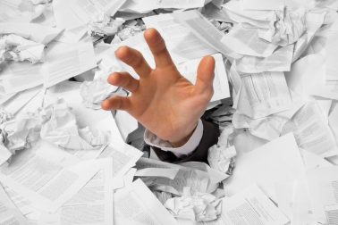 Hand reaches out from big heap of crumpled papers