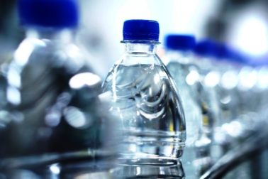 Clean water in plastic bottle moves through conveyor factory.