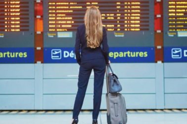 Young woman in international airport near large information display