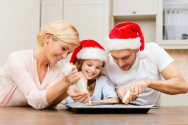 happy family in santa helper hats making cookies