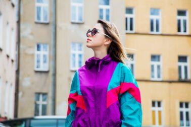 Young woman in jacket of 90s style stay at  back yard of house in East Europe