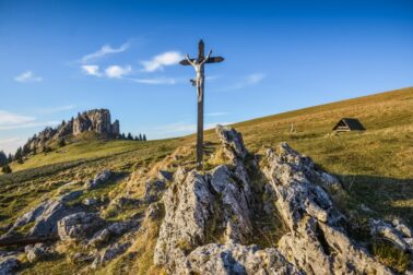 Cross with Jesus Christ on the meadow in mountains
