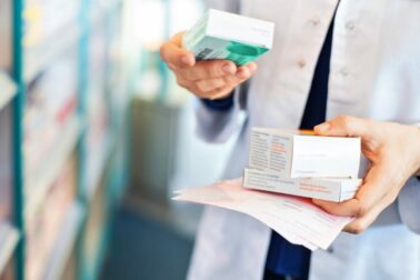 Closeup of pharmacist's hands taking medicines from shelf at the pharmacy