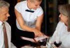 Young waitress shows the menu to mature couple